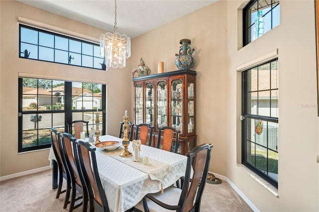 carpeted dining room featuring plenty of natural light, a chandelier, and a high ceiling