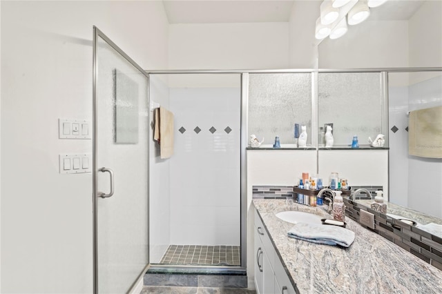 bathroom featuring a shower with door and vanity