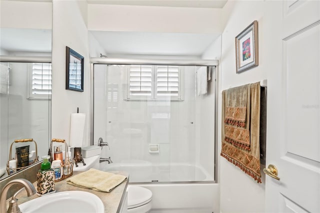 full bathroom featuring vanity, bath / shower combo with glass door, and toilet