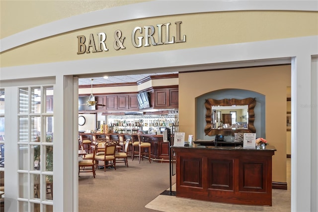 bar with hanging light fixtures and carpet