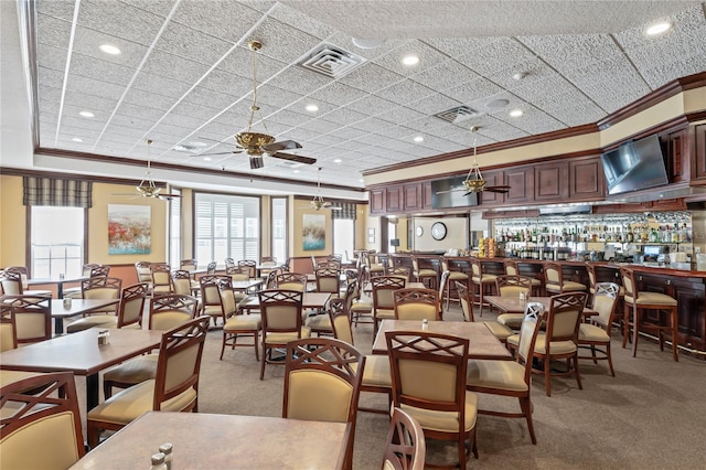 dining room with crown molding, carpet, bar, and ceiling fan