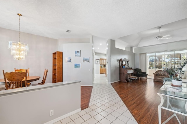 kitchen with ceiling fan with notable chandelier, a textured ceiling, light tile patterned floors, and decorative light fixtures