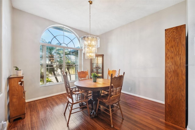 dining space with dark wood-type flooring and an inviting chandelier