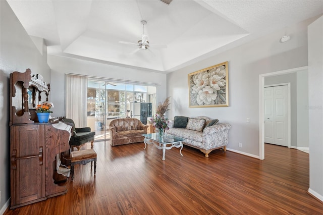 living room featuring hardwood / wood-style floors, a raised ceiling, and ceiling fan