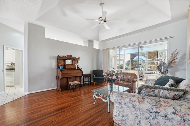 living room featuring dark hardwood / wood-style floors, ceiling fan, and a tray ceiling