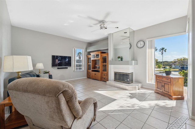 living room featuring ceiling fan, a tile fireplace, and light tile patterned floors