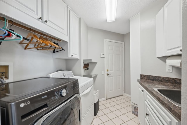 laundry area with sink, cabinets, washer and clothes dryer, light tile patterned floors, and a textured ceiling