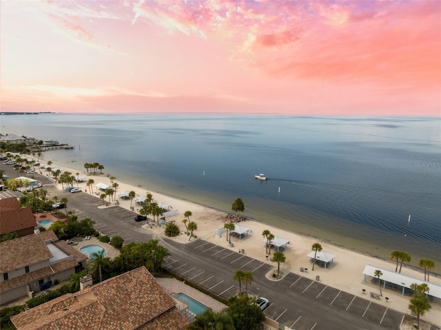 aerial view at dusk with a water view and a beach view