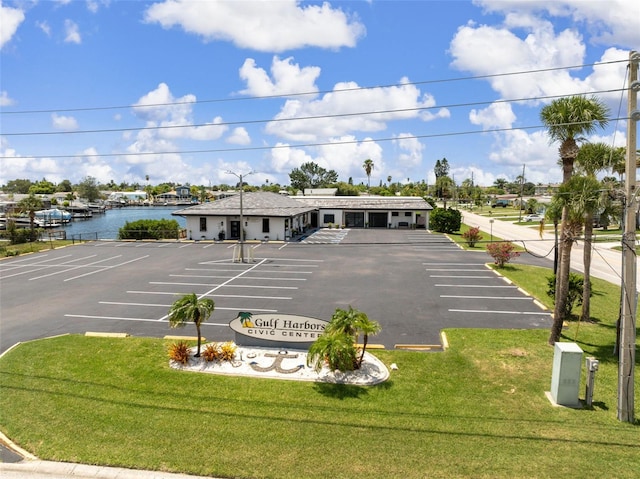 view of parking featuring a water view and a lawn