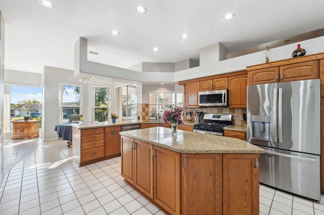 3912 Rudder Way, New Port Richey, FL 34652 - kitchen featuring stainless steel appliances, a peninsula, decorative backsplash, light stone counters, and a center island