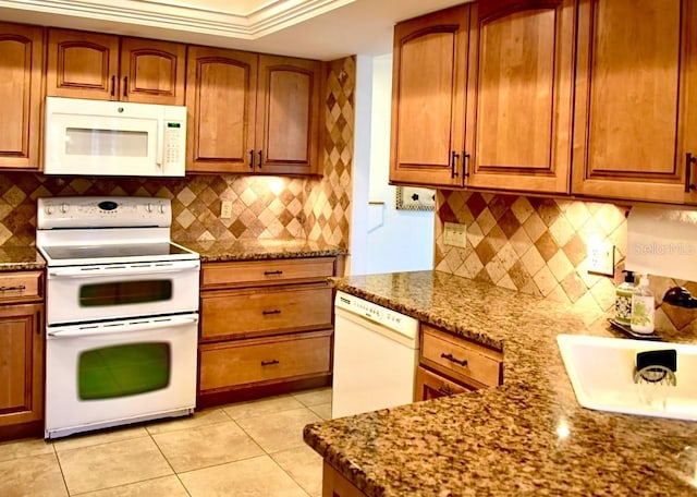 kitchen with stone counters, backsplash, and white appliances