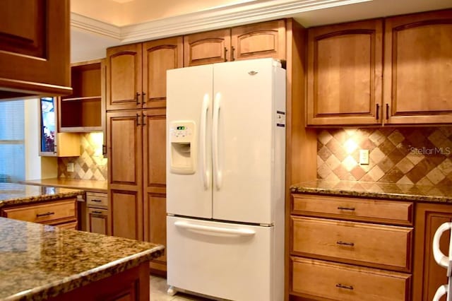 kitchen featuring decorative backsplash, white refrigerator with ice dispenser, and stone counters