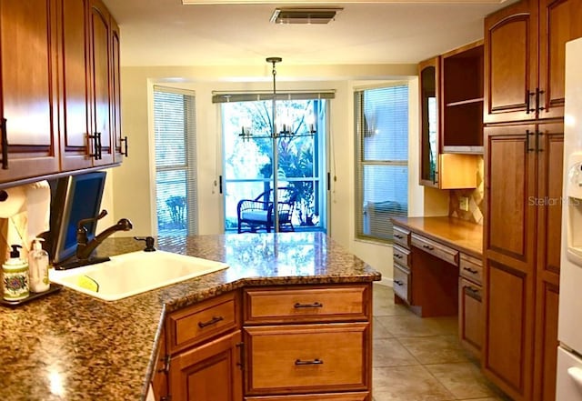 kitchen with built in desk, sink, hanging light fixtures, light tile patterned floors, and a notable chandelier