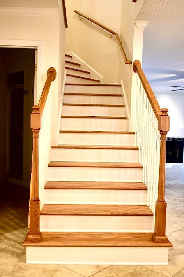 stairs with ornamental molding and a textured ceiling