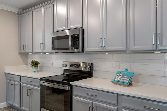 kitchen featuring crown molding, light stone counters, decorative backsplash, and appliances with stainless steel finishes