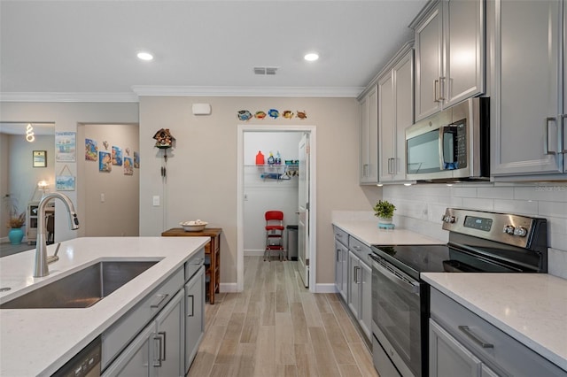 kitchen with stainless steel appliances, gray cabinets, sink, and light stone countertops