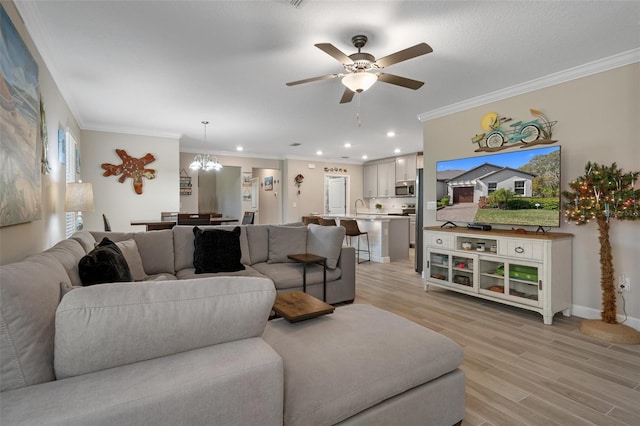 living room featuring sink, crown molding, ceiling fan with notable chandelier, and light hardwood / wood-style floors