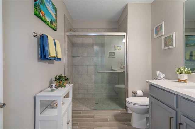 bathroom featuring vanity, toilet, an enclosed shower, and a textured ceiling