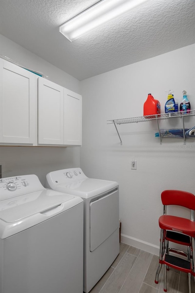 laundry area with washer and clothes dryer, cabinets, and a textured ceiling