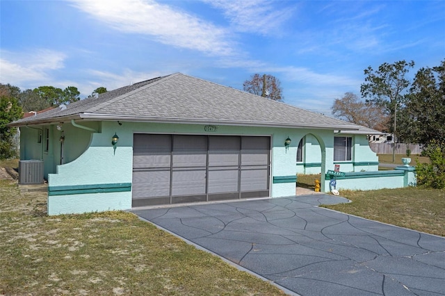 ranch-style house featuring a garage, central AC, and a front yard