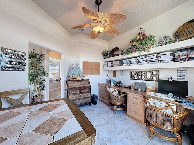 office space featuring light tile patterned flooring, ceiling fan, built in desk, and a textured ceiling