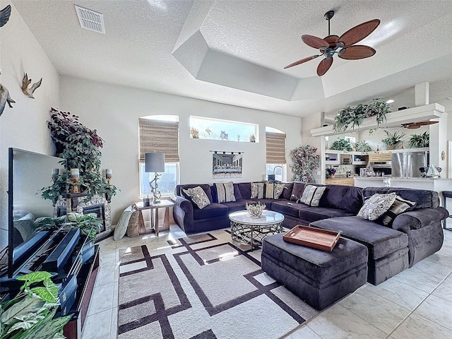 living room featuring ceiling fan, a tray ceiling, and a textured ceiling