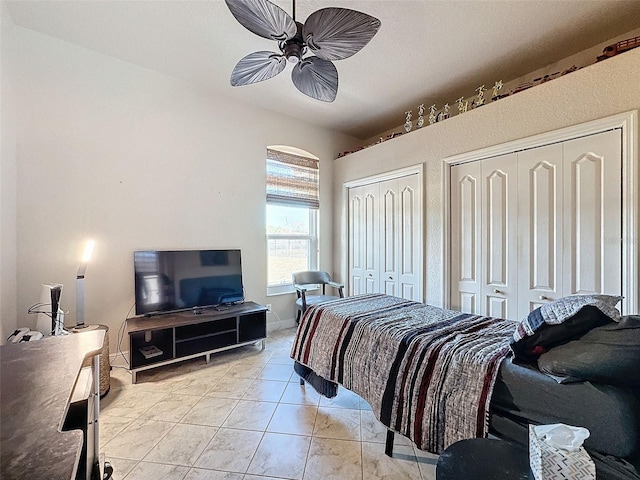 bedroom with multiple closets, ceiling fan, and light tile patterned floors