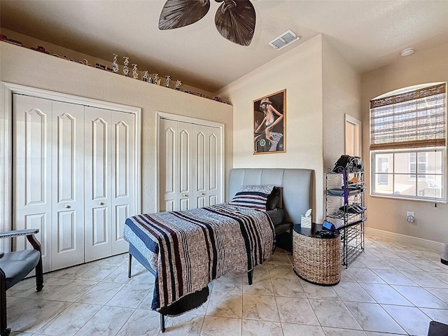 tiled bedroom with ceiling fan and two closets