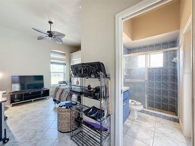 bathroom with tile patterned flooring, walk in shower, ceiling fan, and toilet