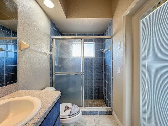 bathroom with vanity, toilet, a shower with door, and a textured ceiling