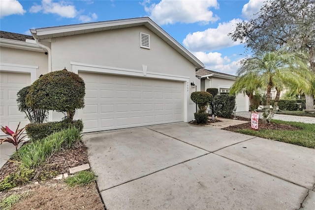 view of side of home with a garage, driveway, and stucco siding