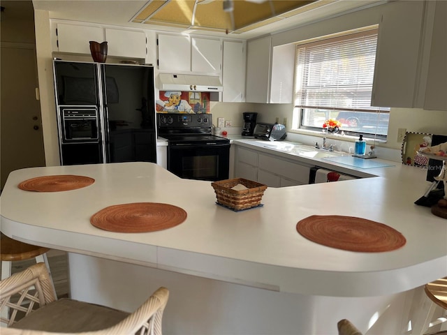 kitchen with a breakfast bar, sink, white cabinetry, kitchen peninsula, and black appliances