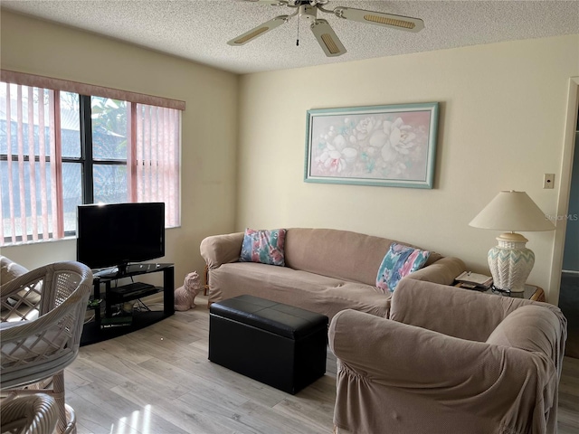 living room with ceiling fan, light hardwood / wood-style flooring, and a textured ceiling