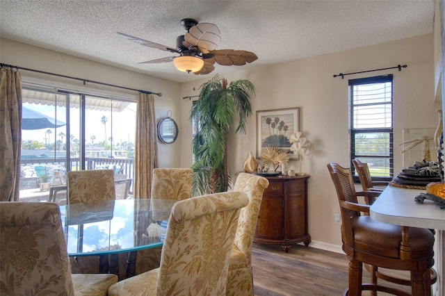 dining room with a textured ceiling, ceiling fan, wood finished floors, and baseboards