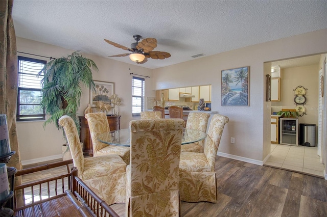 dining area with beverage cooler, a textured ceiling, visible vents, and wood finished floors