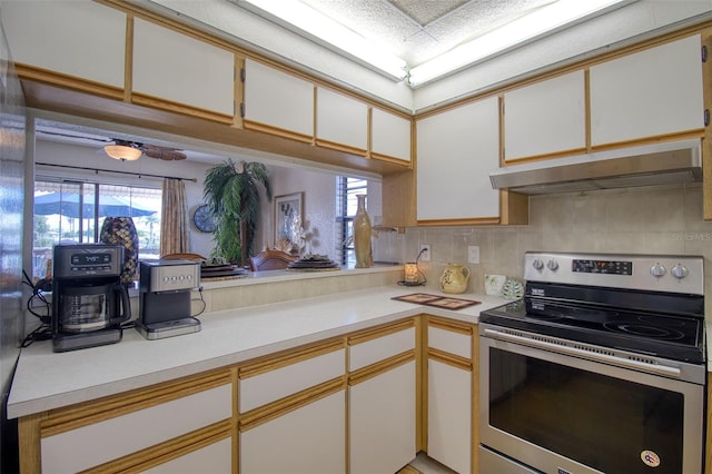 kitchen featuring light countertops, stainless steel electric range, decorative backsplash, and under cabinet range hood