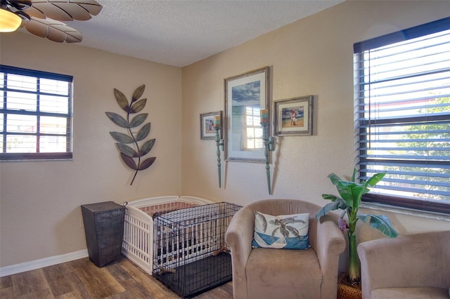 living area with a textured ceiling, baseboards, and wood finished floors