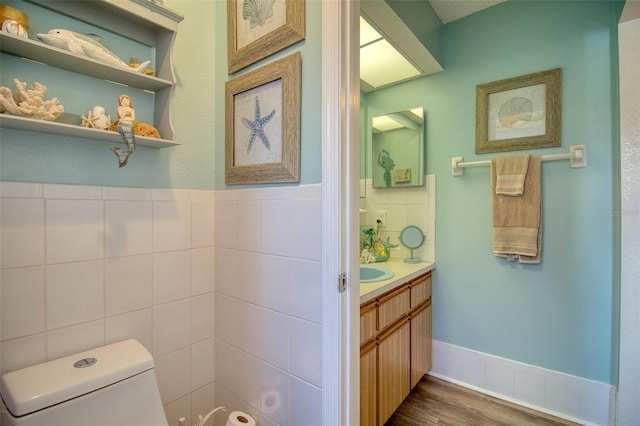 bathroom with vanity, toilet, wood-type flooring, and tile walls