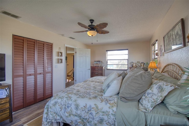 bedroom featuring ceiling fan, wood-type flooring, a closet, and a textured ceiling