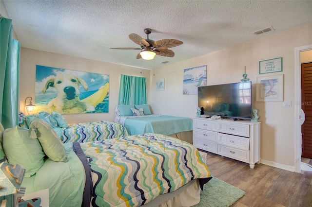 bedroom with ceiling fan, hardwood / wood-style flooring, and a textured ceiling