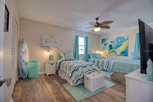 bedroom with ceiling fan, wood-type flooring, and a textured ceiling