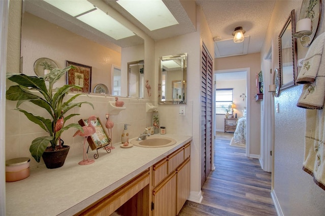 bathroom featuring a skylight, a textured ceiling, vanity, hardwood / wood-style floors, and backsplash