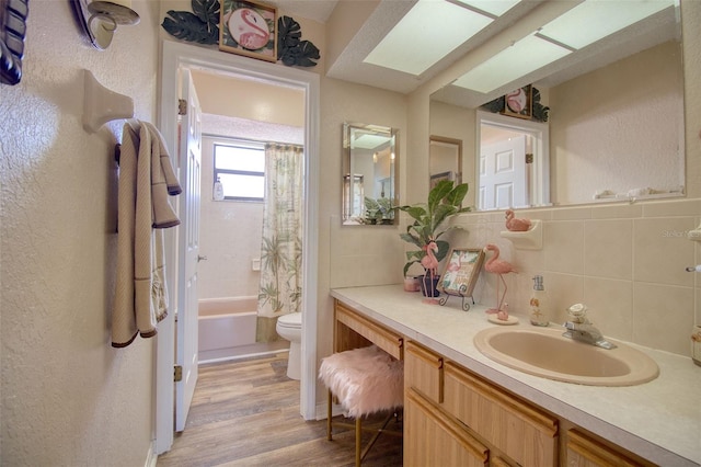 bathroom featuring tile walls, toilet, shower / tub combo, vanity, and wood finished floors