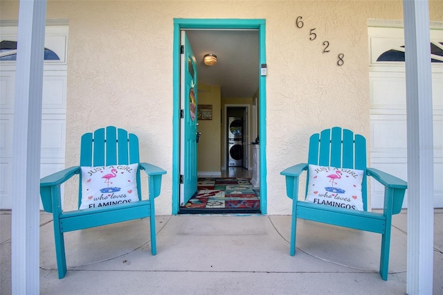 view of exterior entry featuring washer / clothes dryer and stucco siding