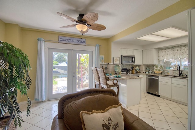 kitchen with sink, appliances with stainless steel finishes, light stone counters, white cabinets, and light tile patterned flooring