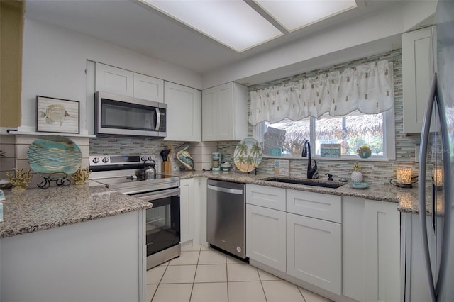 kitchen with appliances with stainless steel finishes, a sink, white cabinetry, and decorative backsplash