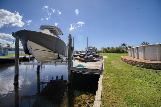 view of dock featuring a water view, boat lift, and a yard