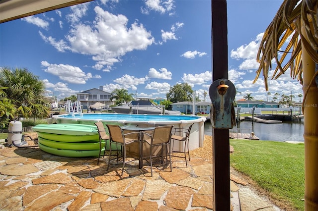 outdoor pool featuring a yard, a patio area, and a water view