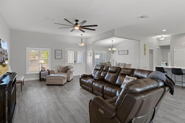 living room featuring ceiling fan with notable chandelier and light hardwood / wood-style flooring