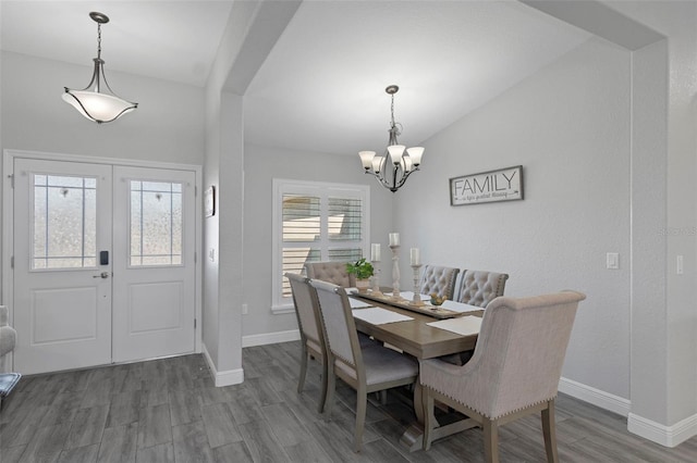 dining space with lofted ceiling, a notable chandelier, hardwood / wood-style flooring, and french doors